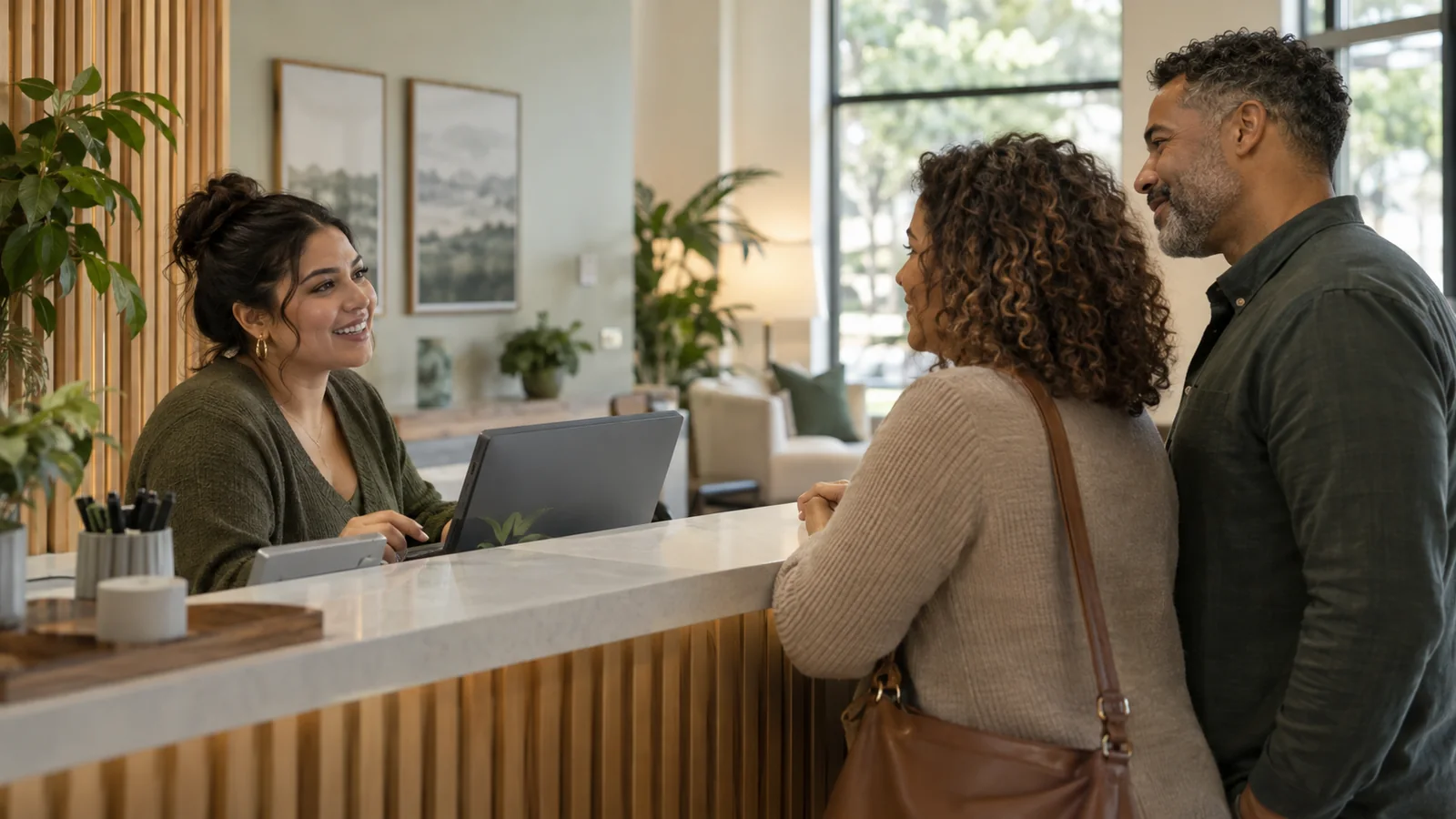 An admissions counselor welcoming a family at the front desk of a treatment center
